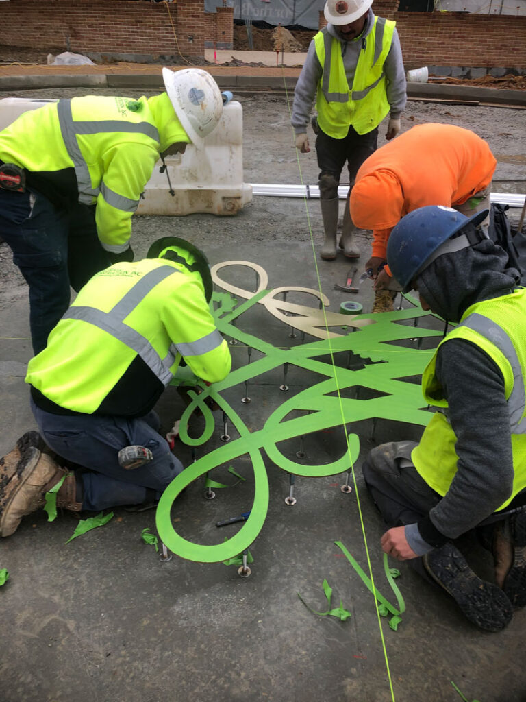 Men preparing a decorative bronze insert to be placed in concrete